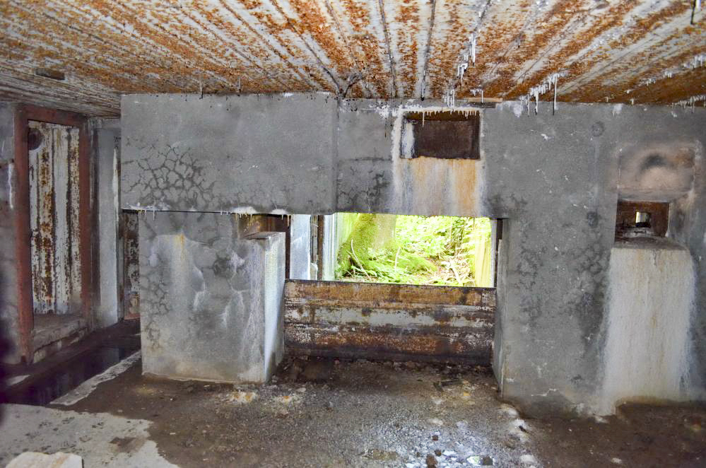 Ligne Maginot - Blockhaus STG 105 - Breitenhag - Entrée matériel fermée avec des rails. A gauche l'entrée des hommes avec les toilettes et sa fosse, à droite le créneau de tir FM de la chambre de tir mitrailleuse  nord. Au sol, entre l'entrée matériel et le créneau de tir FM, on distingue l'arrivée des câbles. - D. Froehly