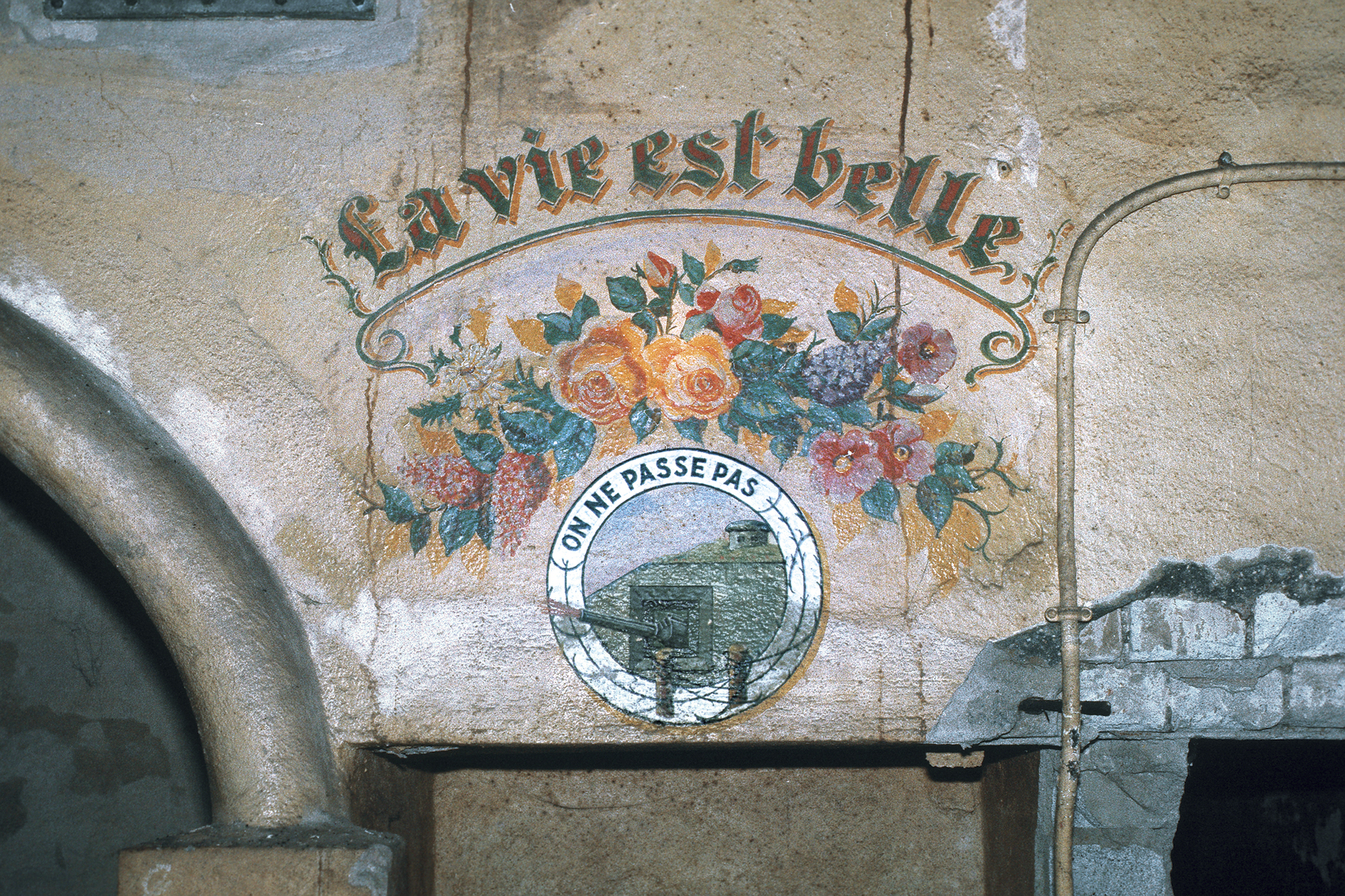 Ligne Maginot - KOBENBUSCH  - A13 - (Ouvrage d'artillerie) - La célèbre peinture murale 'La vie est belle' en chef d'un magnifique bouquet de fleurs et de l'insigne des troupes de forteresse. Photo faite en 1985 quelques jours avant l'inondation de l'ouvrage. - Frédéric Lisch