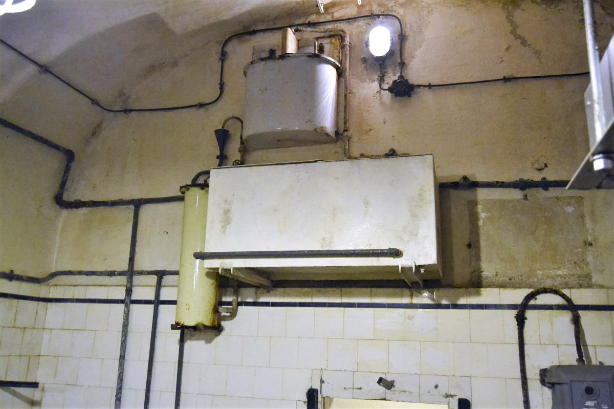 Ligne Maginot - GALGENBERG - A15 - (Ouvrage d'artillerie) - La cuisine troupe
Installation carbone-chlore de traitement de l'eau. La partie supérieure est le système de dosage du chlore. Une fois le mélange fait, celui ci passe au travers du filtre à charbon actif (tube sur la gauche de la photo) puis est stocké dans la citerne de couleur blanche en bas de la photo