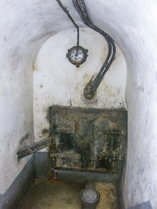 Ligne Maginot - BIRLENBACH - (Abri) - Le départ des égouts
La galerie d'égout sert d'entrée pour les cables téléphoniques. Ceux ci sont visibles au dessus de la porte. - Pascal LAMBERT